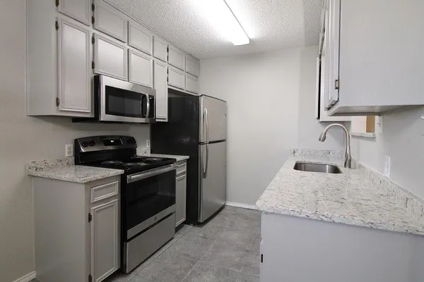 a kitchen with stainless steel appliances granite countertop a sink stove microwave and refrigerator