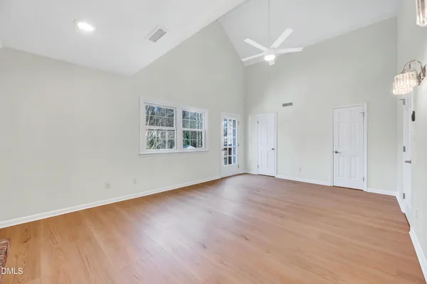 an empty room with wooden floor a ceiling fan and windows