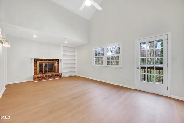 a view of an empty room with a window and fireplace