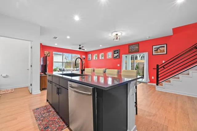 a kitchen with stainless steel appliances kitchen island granite countertop a sink and dishwasher a stove with wooden floor