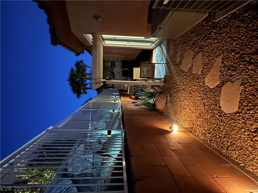 977 Rhyolite Terrace Henderson, NV 89011 - Photo 31 of 33 An inviting stone-paved walkway winds alongside the home under warm outdoor lighting.