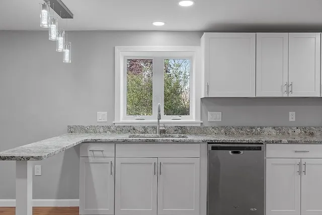 a kitchen with granite countertop white cabinets and a window