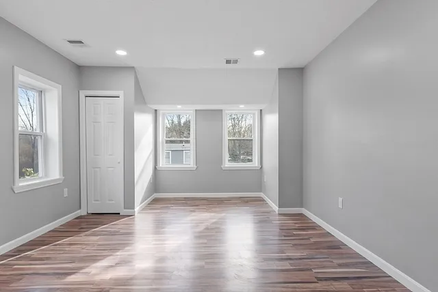 an empty room with wooden floor and windows