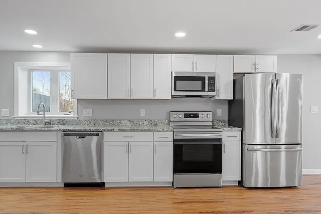 a kitchen with granite countertop a refrigerator stove and microwave