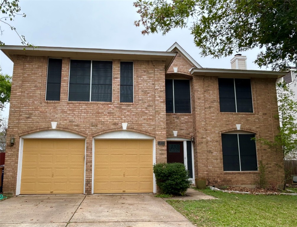 Colonial inspired home featuring concrete driveway, a chimney, brick siding, and an attached garage