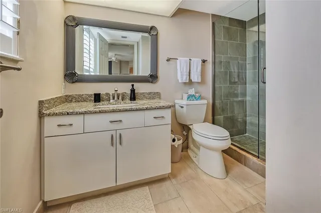 a bathroom with a granite countertop toilet sink and mirror