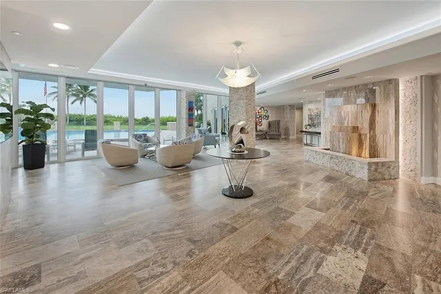 a room with lots of white furniture a chandelier and a view of living room
