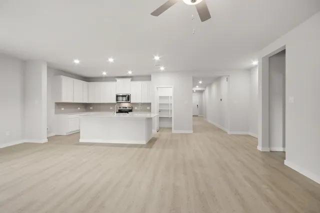 a view of kitchen with kitchen island wooden floor center island and stainless steel appliances