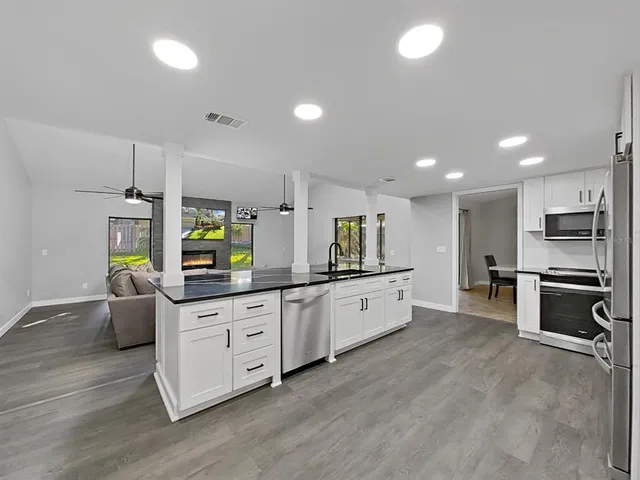 a large kitchen with stainless steel appliances a large counter top a stove a chimney a sink and a refrigerator