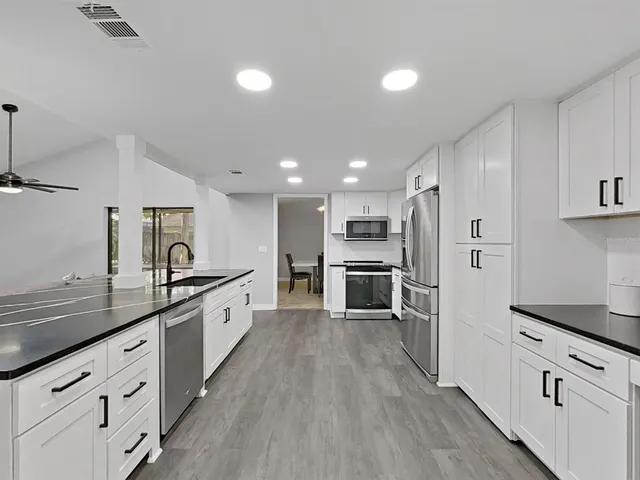 a large kitchen with cabinets wooden floor and stainless steel appliances