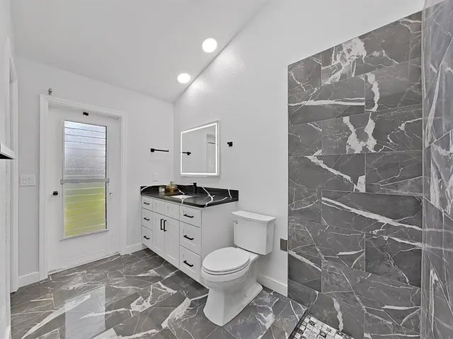 a bathroom with a granite countertop toilet and a shower
