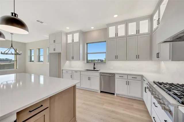 a kitchen with stainless steel appliances granite countertop a sink a stove and a refrigerator