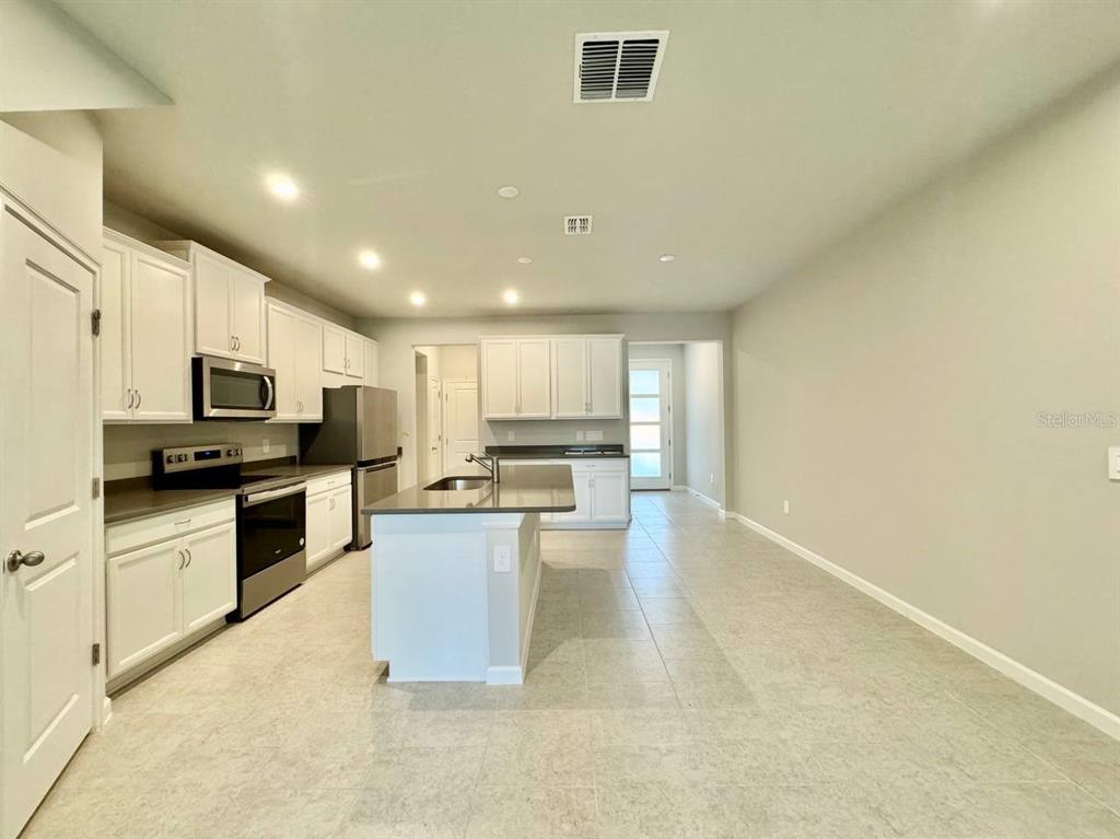 3247 Feather Hvn Place Brandon, FL 33511 - Photo 6 of 34 a kitchen with stainless steel appliances kitchen island granite countertop a stove top oven a sink a dining table and chairs