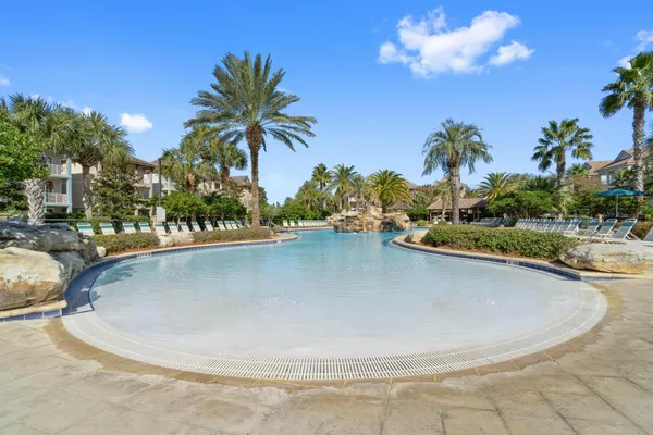 a view of a swimming pool with a yard and palm trees