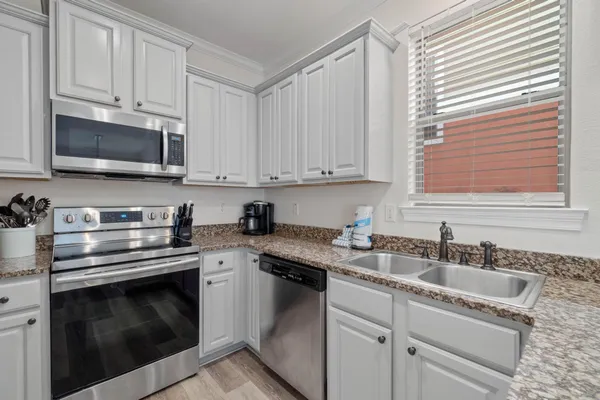 a kitchen with granite countertop white cabinets white stainless steel appliances and a sink
