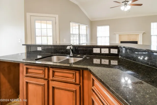 a kitchen with granite countertop a sink and white cabinets