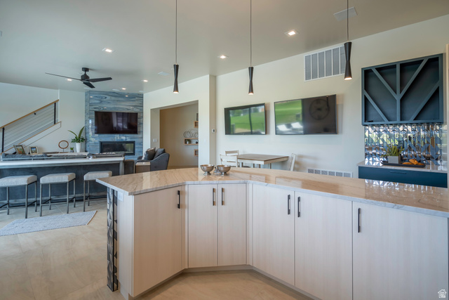 3606 South Cypress Road Hurricane, UT 84737 - Photo 68 of 69 Kitchen with open floor plan, light stone countertops, ceiling fan, a fireplace, and hanging light fixtures