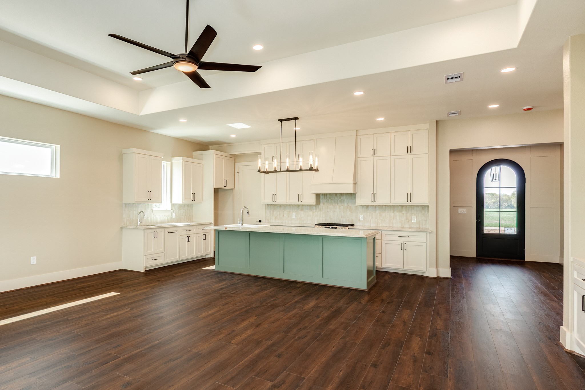 1737 Flintlock Court Angleton, TX 77515 - Photo 15 of 47 This spacious kitchen features modern custom cabinetry, a large island for entertaining, and elegant quartzite Taj Mahal countertops. The open layout is enhanced by dark wood flooring, recessed lighting, a ceiling fan, and a stylish light fixture. This space creates a warm and inviting space.