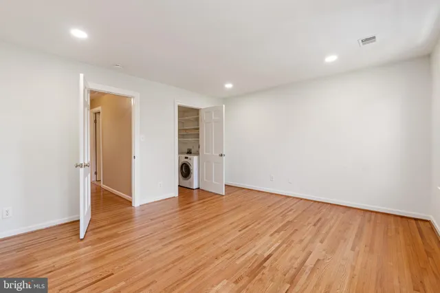 a view of an empty room with wooden floor and closet