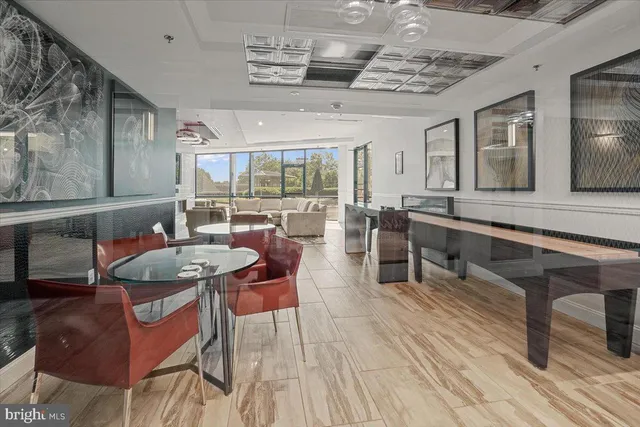 a dining hall with stainless steel appliances kitchen island granite countertop a table chairs and a view of living room