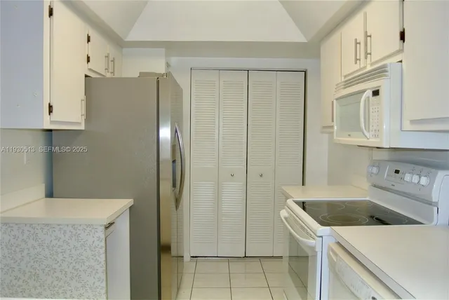 a kitchen with stainless steel appliances granite countertop a refrigerator a stove and white cabinets