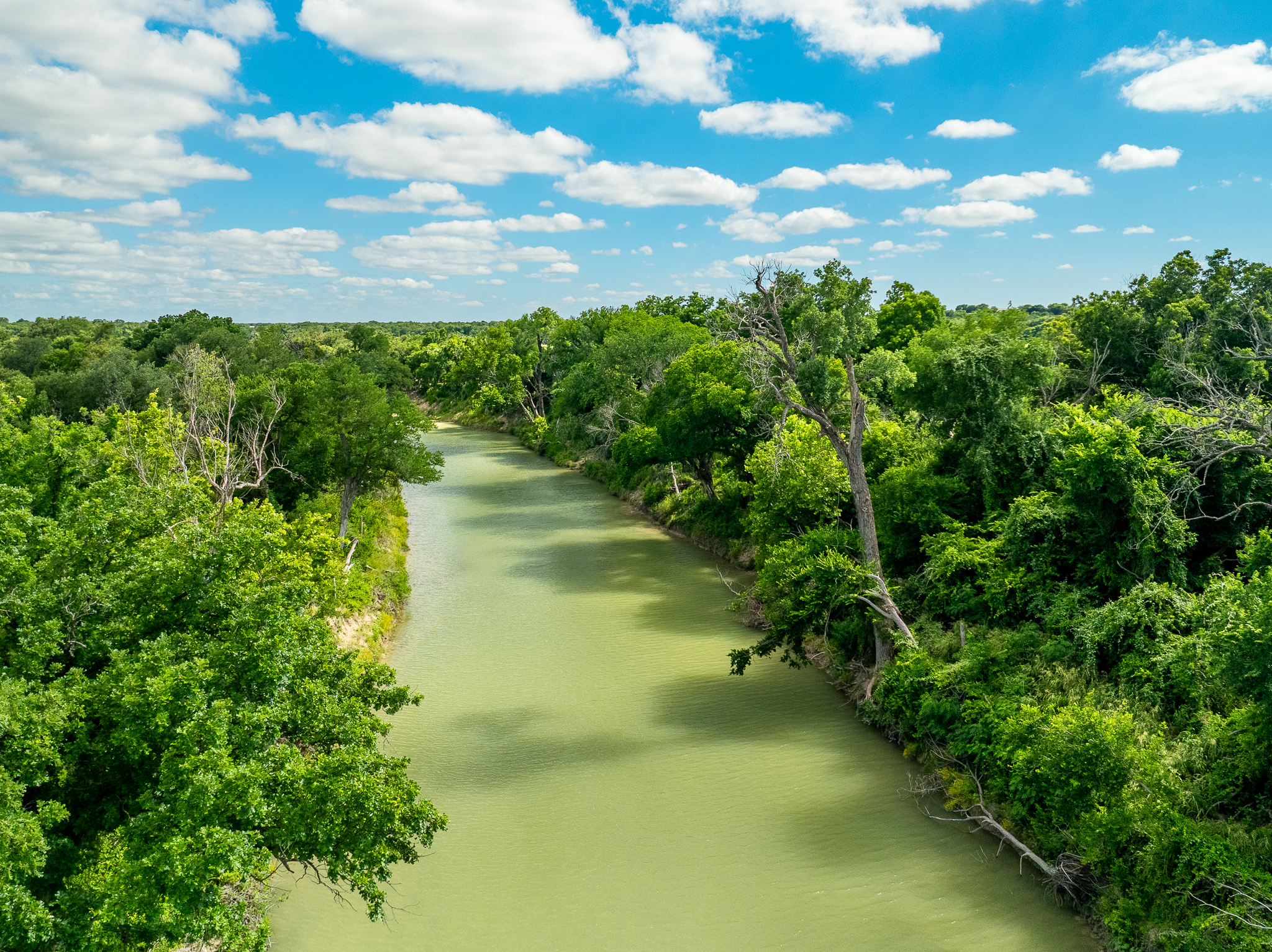 8044 580th Street East Kempner, TX 76539 - Photo 28 of 40 A tranquil river winds through a verdant landscape under a bright, cloud-dotted sky.