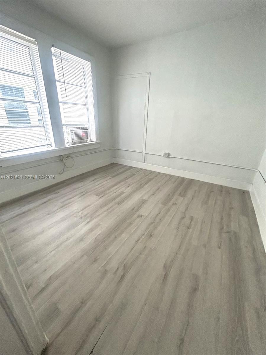 967 Southwest 5th Street, Unit 10 Miami, FL 33130 - Photo 6 of 9 an empty room with wooden floor and windows