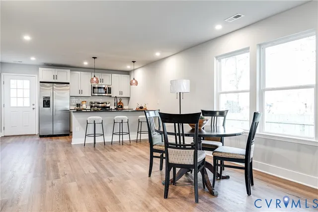 a kitchen with stainless steel appliances granite countertop a stove top oven a sink dishwasher and a dining table with wooden floor