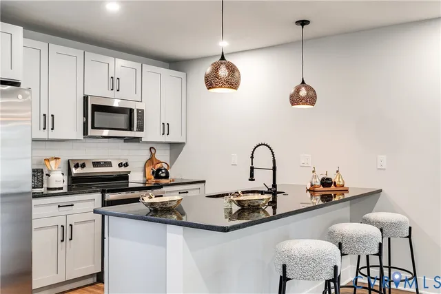 a kitchen with stainless steel appliances granite countertop a stove a sink and a white cabinets