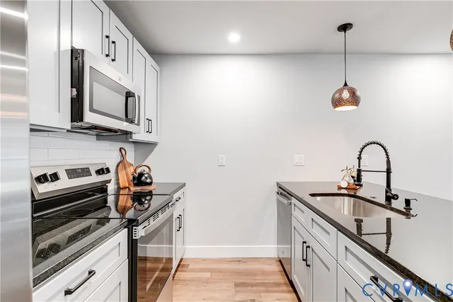 a kitchen with stainless steel appliances granite countertop a sink a stove and a wooden floors