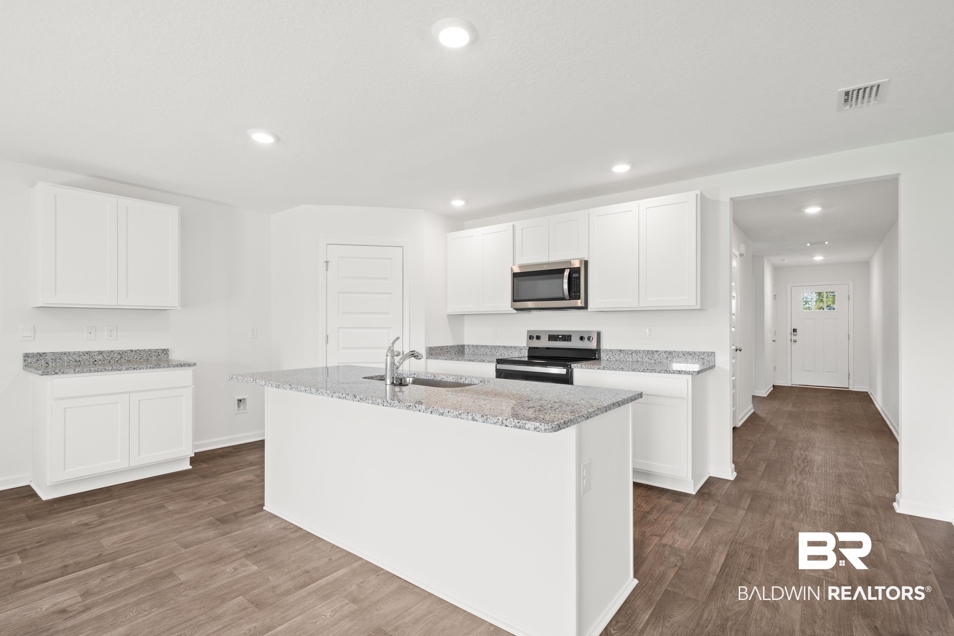 14615 Dayton Circle Foley, AL 36535 - Photo 14 of 27 Kitchen featuring an island with a stainless steel sink, granite countertops, and white cabinetry