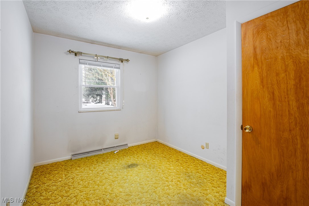 5905 Renninger Road New Franklin, OH 44319 - Photo 11 of 31 Spare room featuring baseboard heating, carpet, and a textured ceiling