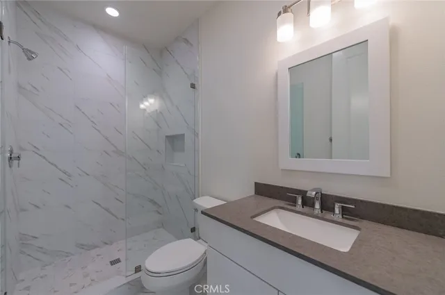 a bathroom with a granite countertop sink a toilet and a mirror