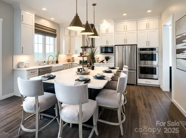 a dining room with stainless steel appliances kitchen island granite countertop a table chairs and a refrigerator