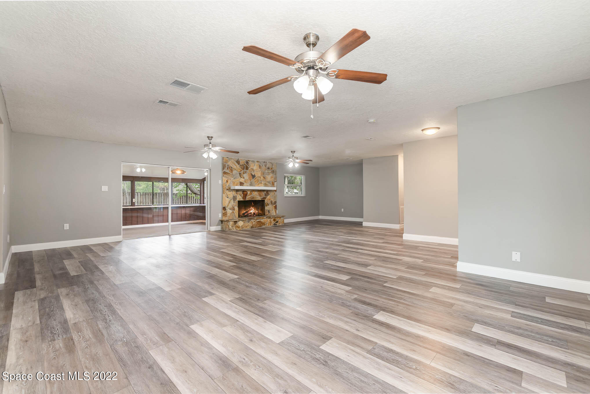 2380 Friday Road Cocoa, FL 32926 - Photo 12 of 30 an empty room with wooden floor chandelier fan and windows