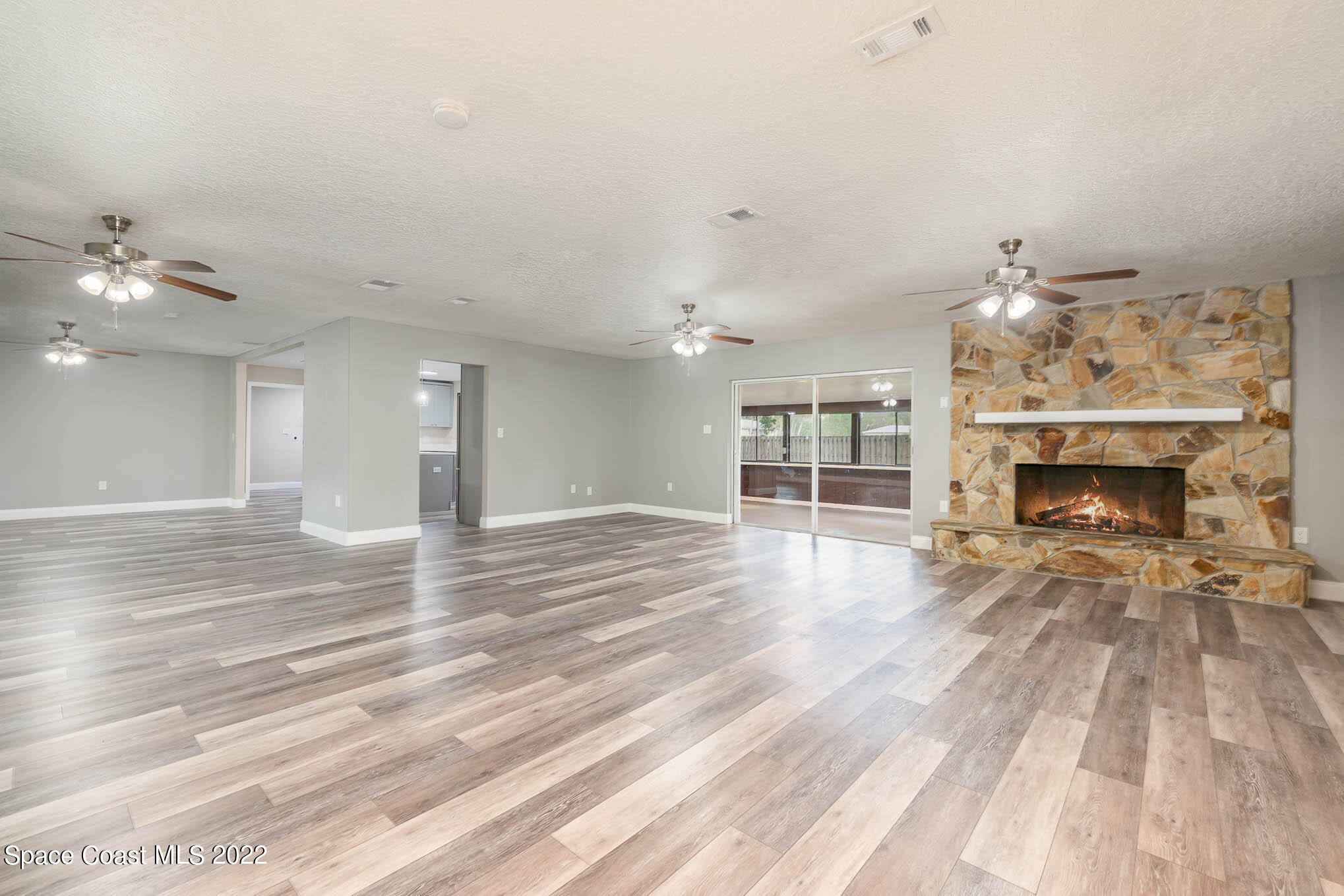 2380 Friday Road Cocoa, FL 32926 - Photo 10 of 30 an empty room with wooden floor fireplace and chandelier
