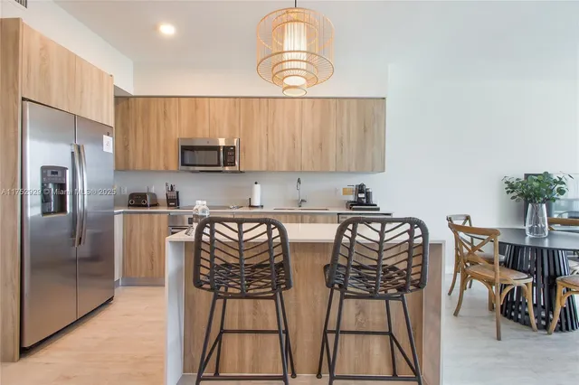 a kitchen with stainless steel appliances granite countertop a stove a refrigerator a sink a dining table and chairs with wooden floor