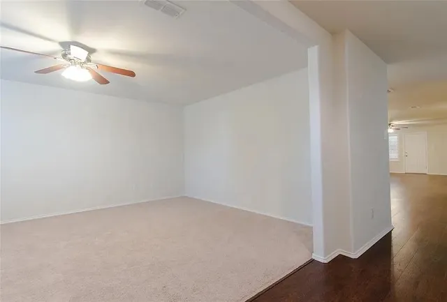 an empty room with wooden floor and fan