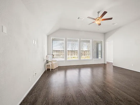 an empty room with wooden floor fan and windows
