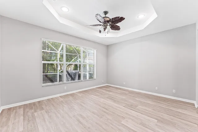 a view of an empty room with wooden floor and a ceiling fan