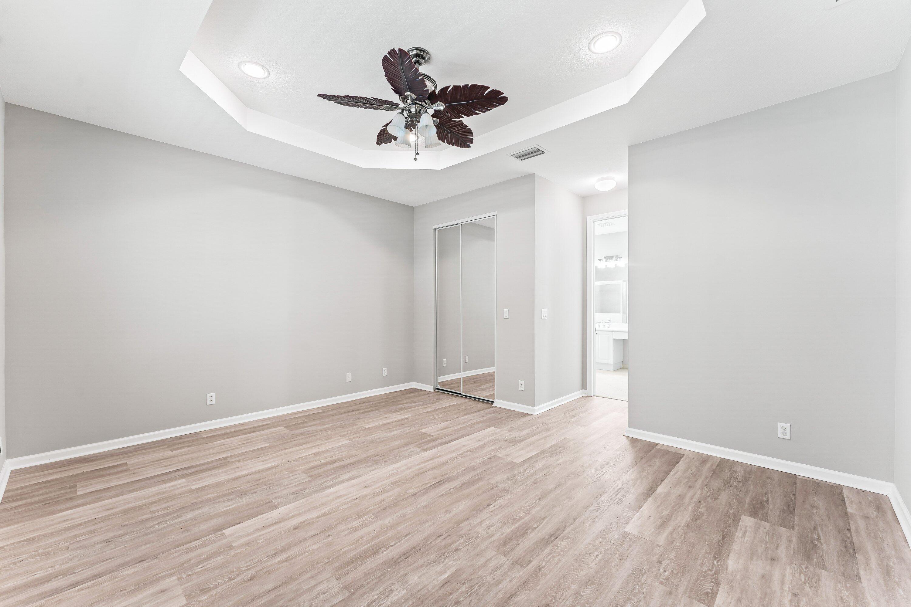 443 Belle Grove Lane West Palm Beach, FL 33411 - Photo 20 of 29 a view of an empty room with wooden floor and a ceiling fan
