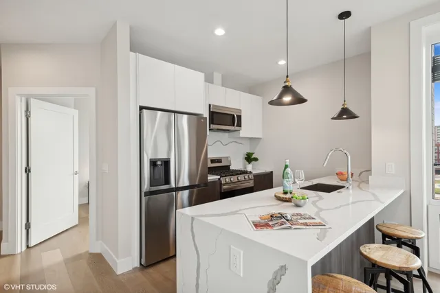 a kitchen with stainless steel appliances kitchen island granite countertop a sink and a living room view