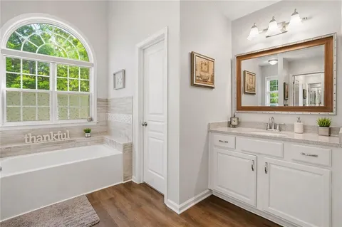a bathroom with a tub a sink and mirror