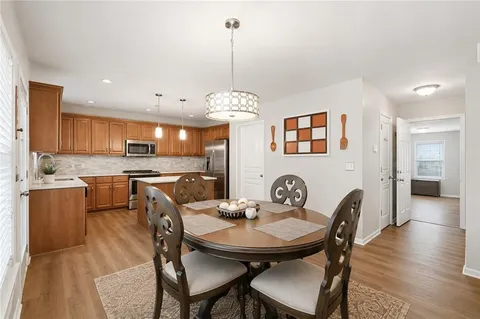 a view of a dining room and livingroom with furniture wooden floor a rug a painting and a chandelier