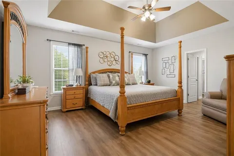 a bedroom with a bed wooden floor and windows