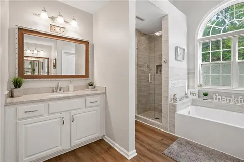 a bathroom with a granite countertop tub a sink and a large mirror