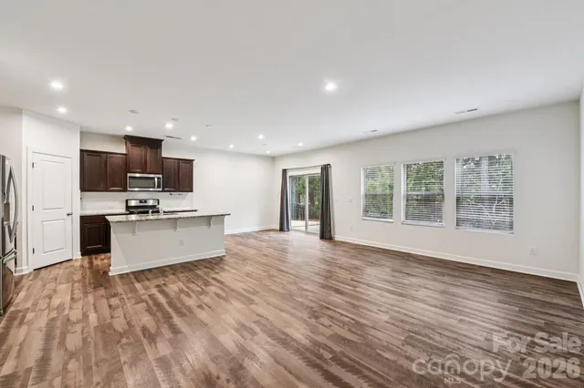 a large white kitchen with kitchen island a sink wooden floor and stainless steel appliances