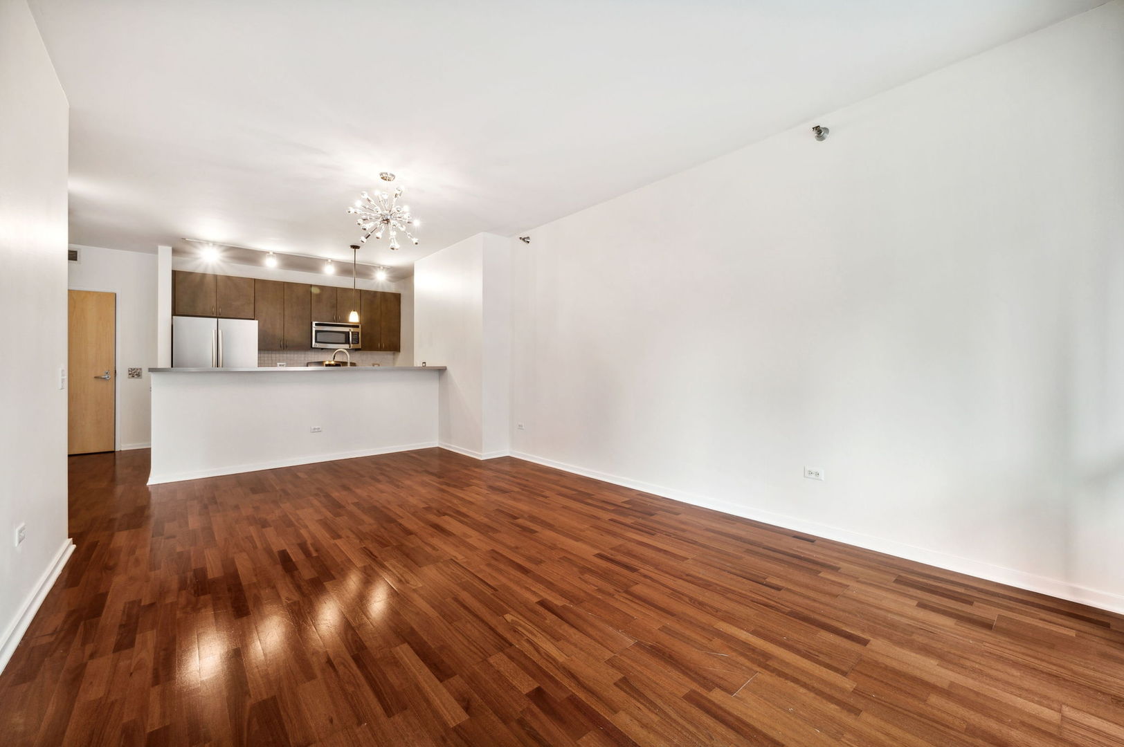 123 South Green Street, Unit 407B Chicago, IL 60607 - Photo 6 of 20 a view of kitchen and empty room with wooden floor