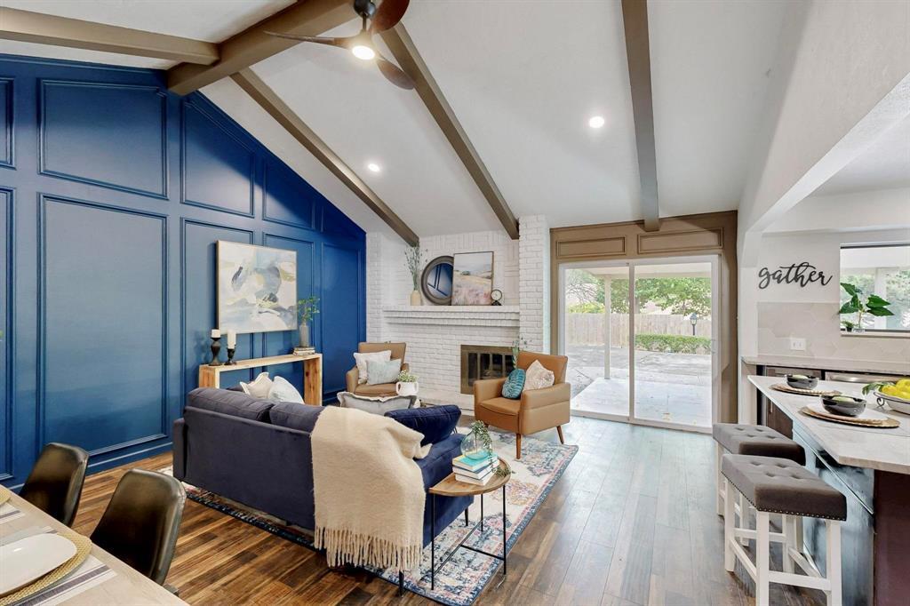3965 Singleleaf Lane Fort Worth, TX 76133 - Photo 31 of 39 Vaulted ceiling with exposed wood beams, accent wall with panel molding, wood-finish flooring, brick fireplace surround, and sliding glass doors to the exterior patio