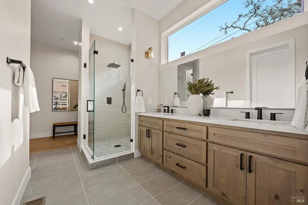 a spacious bathroom with a double vanity sink a mirror and a shower